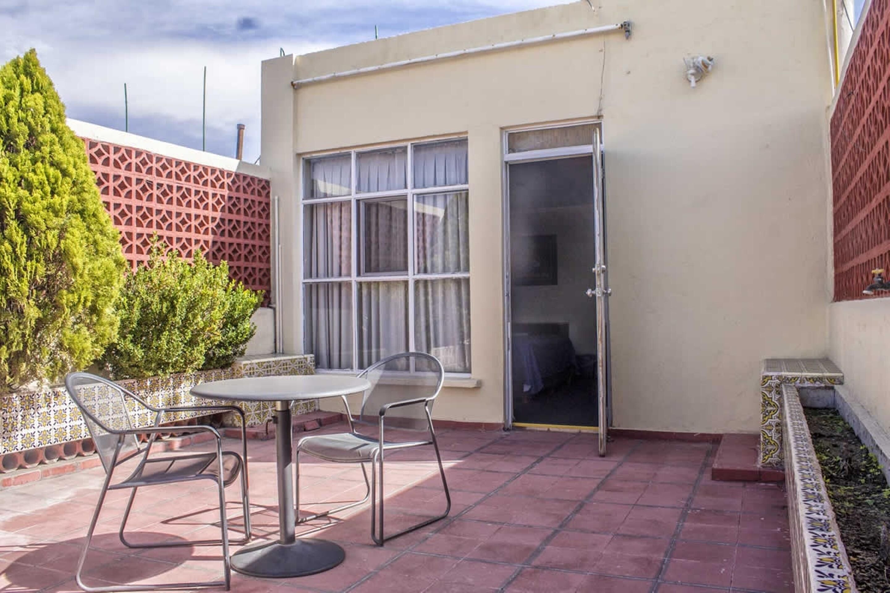 A patio with a table and chairs, a sliding glass door, and a tiled wall.