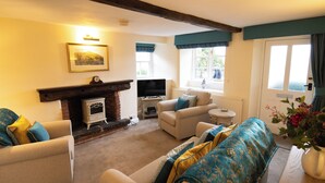 A cozy living room with a fireplace, comfortable seating, and a television. - The Peacock at Barlow (Dronfield)