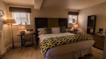 Un dormitorio con una cama grande, dos mesitas de noche con lámparas, un aparador y un espejo.