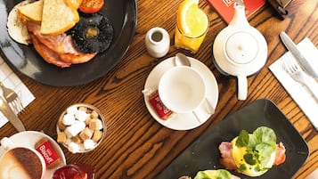 Desayuno con tostadas, huevos y un libro sobre una mesa de madera.