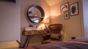 A room with a wooden desk, a leather chair, a round mirror, and framed artwork on the wall. - The Peacock at Barlow (Dronfield)