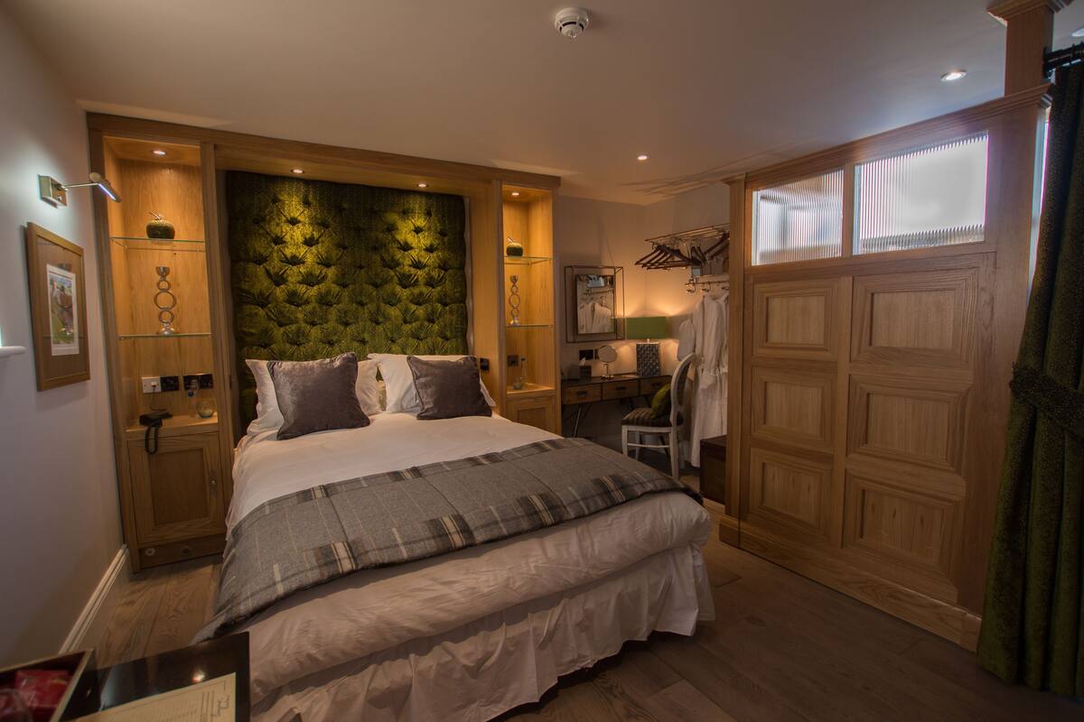 A bedroom with a large bed, wooden headboard, bedside tables, a desk, and a wardrobe.