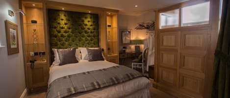 A bedroom with a large bed, wooden headboard, bedside tables, a desk, and a wardrobe.