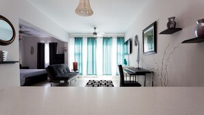 Un soggiorno moderno con un divano, un tavolo da pranzo e una TV. Alle finestre sono presenti delle tende e un lampadario al soffitto.