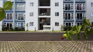 A multi-story residential building with a central staircase, balconies, and a paved entrance area.