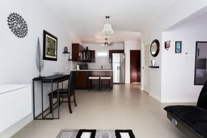 A modern kitchen with a dining area, a black sofa, and a ceiling fan.