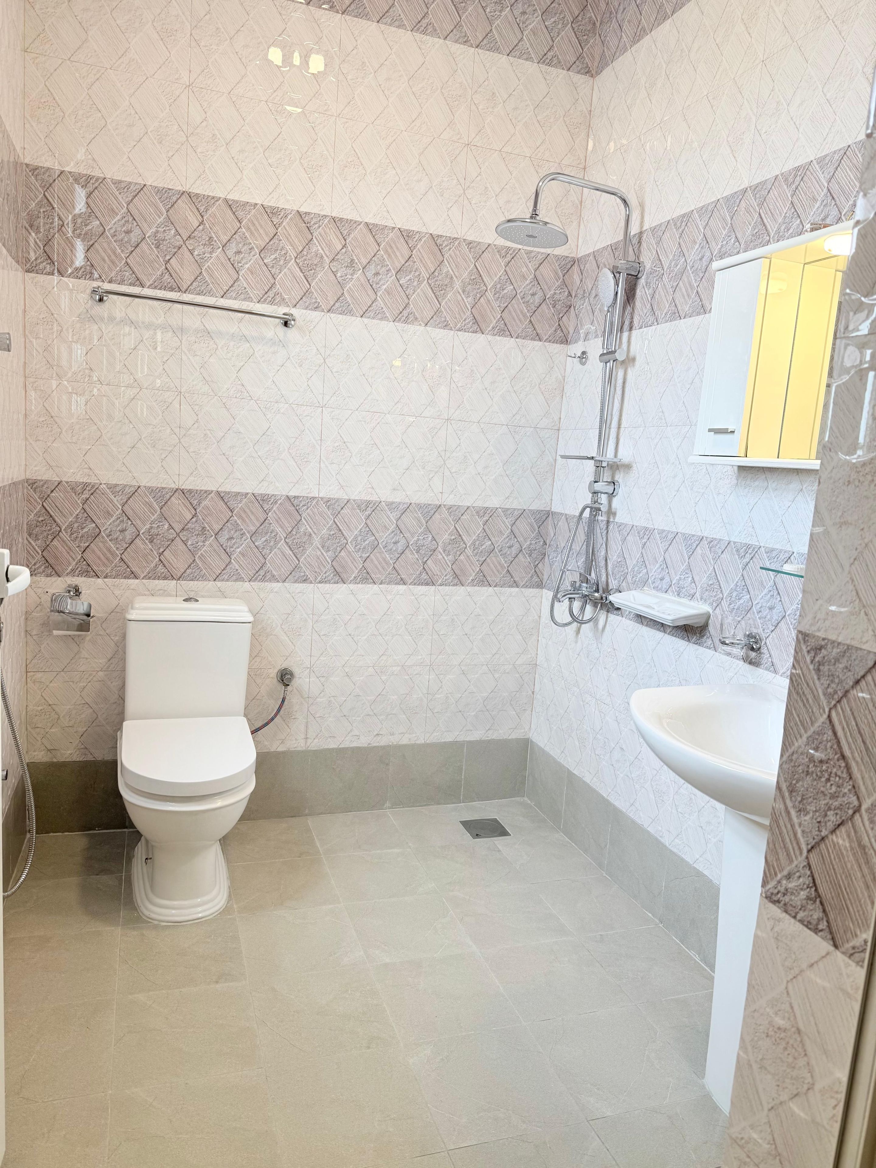 A bathroom with a toilet, shower, and sink.
