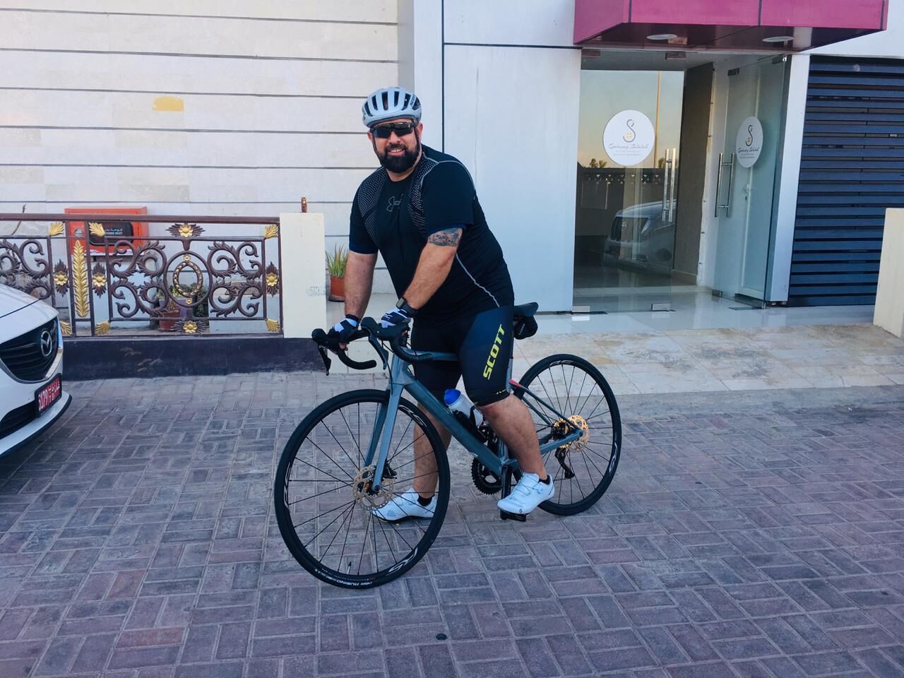 Une personne à vélo devant un bâtiment sur lequel on peut lire l’inscription « S ».