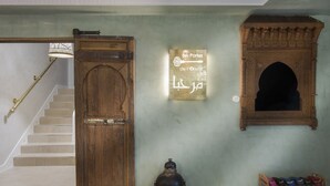 A staircase with a wooden door, a wall-mounted sign, a decorative archway, and a shoe rack. - RIAD SPA Les portes de l'Orient TOURS (Tours)