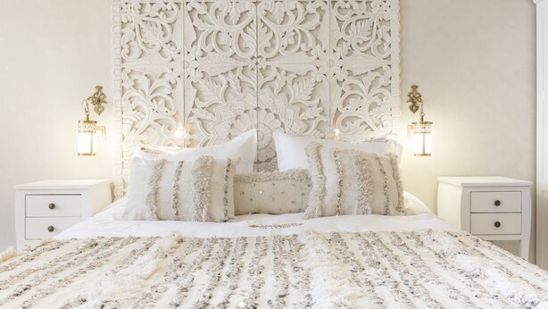 A bedroom with a large bed, ornate headboard, two bedside tables with lamps, and a decorative wall panel. - RIAD SPA Les portes de l'Orient TOURS (Tours)