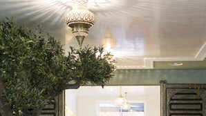 A cozy living area with a large tree, a chandelier, and a view into another room. - RIAD SPA Les portes de l'Orient TOURS (Tours)