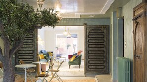 A cozy living room with a tree, a dining table, and chairs. There is a large wooden door and a radiator on the wall. - RIAD SPA Les portes de l'Orient TOURS (Tours)