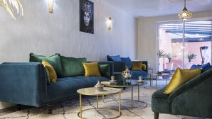 A modern living room with a blue sofa, green armchairs, and a patterned rug. - RIAD SPA Les portes de l'Orient TOURS (Tours)