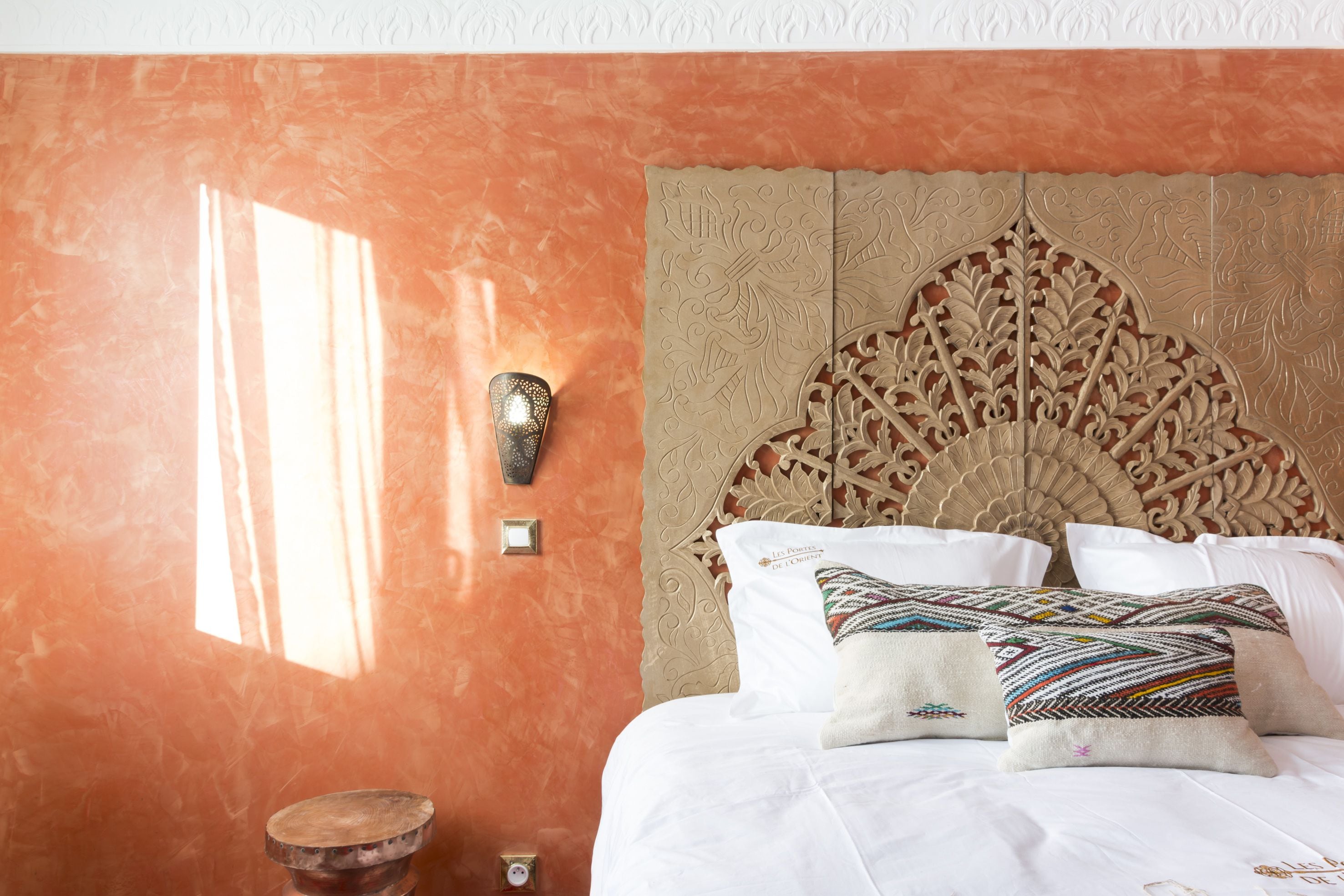 Une chambre à coucher avec un grand lit, une tête de lit décorative et un luminaire fixé au mur.