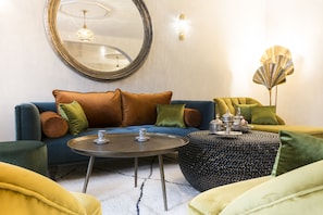 A modern living room with a blue sofa, yellow armchairs, a round coffee table, and a decorative floor lamp. - RIAD SPA Les portes de l'Orient TOURS (Tours)