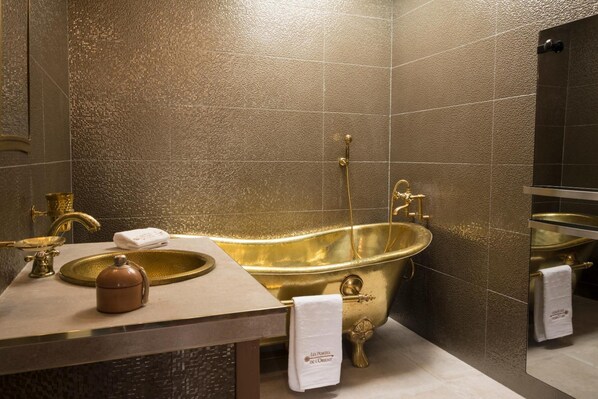 A luxurious bathroom with a gold bathtub, a sink, and a mirror.