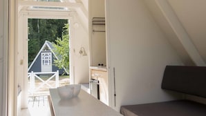 A room with a white ceiling, a window, a white bench, and a small table with a bowl.