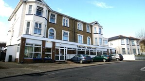 A two-story Channel View Hotel with a white facade, large windows, and a parking area with cars. - Channel View Hotel (Sandown)