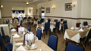 A dining area with multiple tables set for service, chairs, and a ceiling fan. - Channel View Hotel (Sandown)
