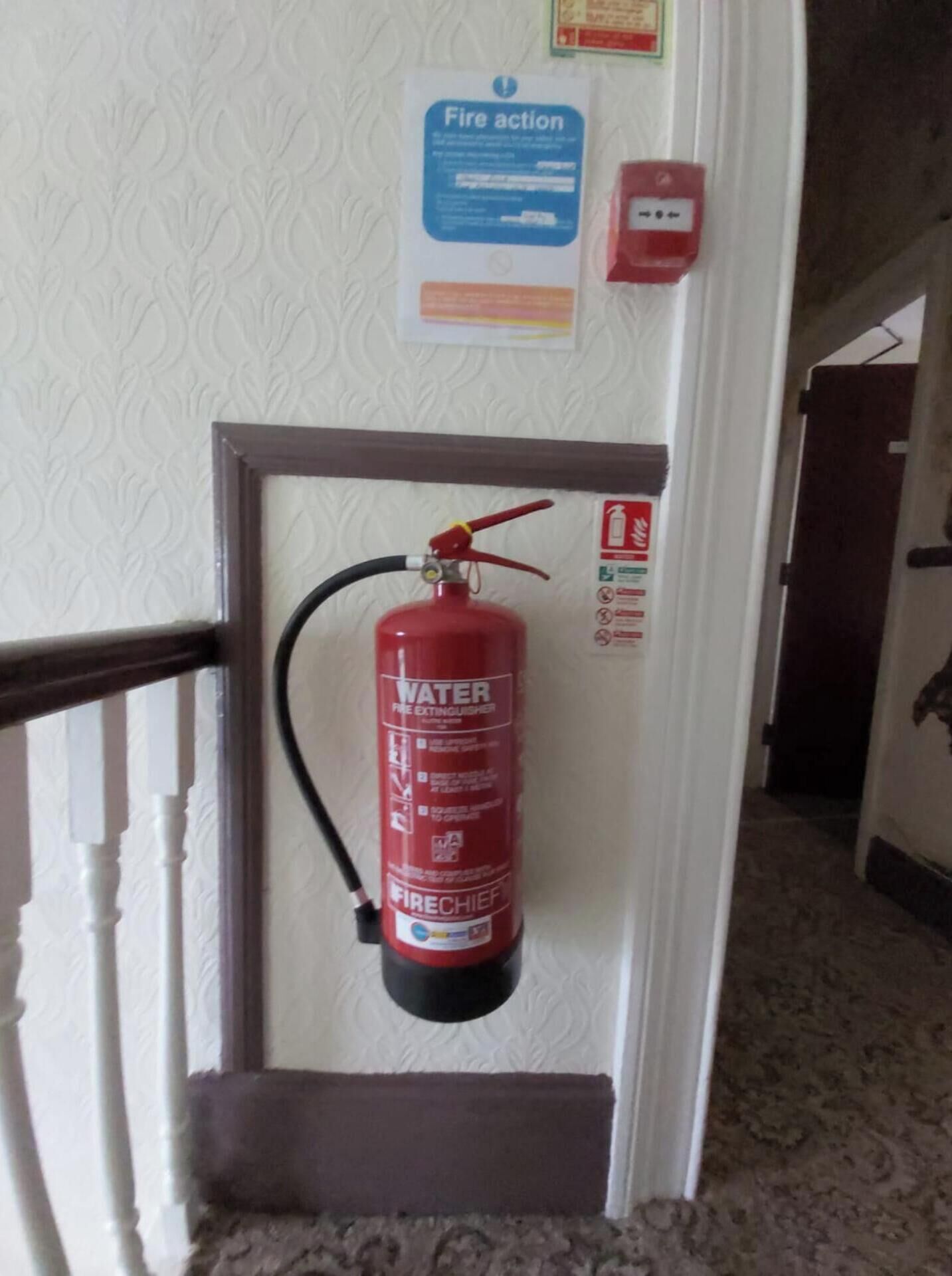 A fire extinguisher mounted on a wall in a hallway.
