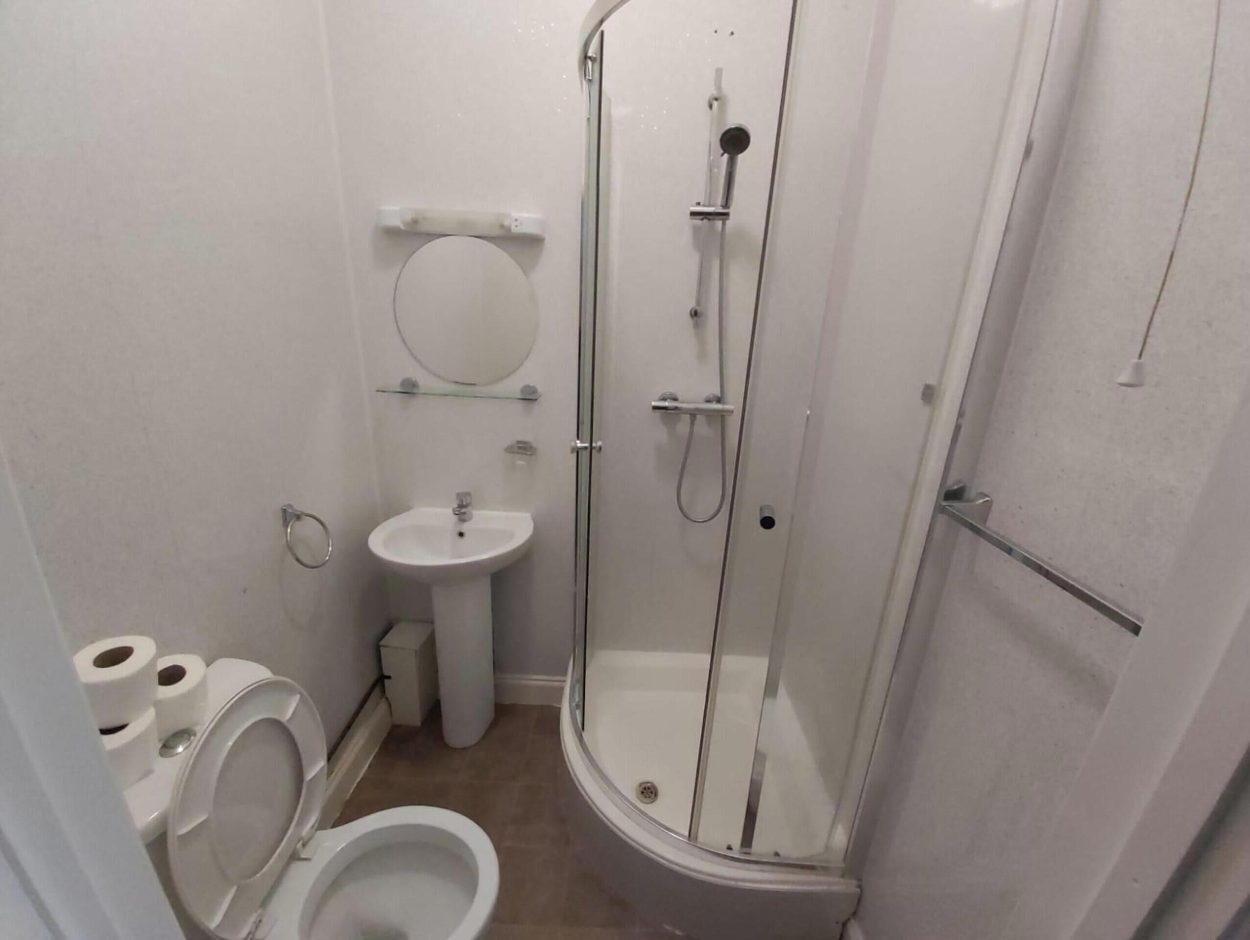 A small, compact bathroom with a toilet, sink, and shower.