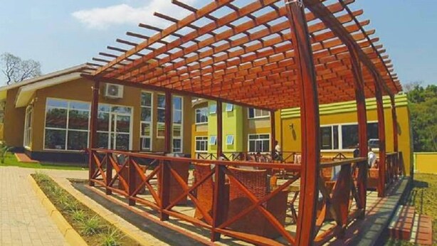 Um edifício com área externa coberta, janelas amplas e um caminho pavimentado.