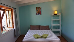 A bedroom with a bed, pillows, a painting, a shelf with a lamp, and a window with curtains. - Ventana Sur Hostel (Santiago)