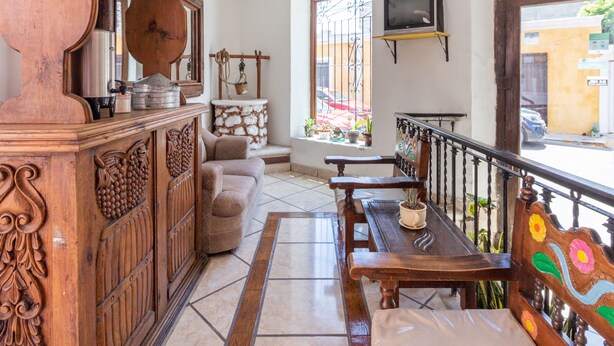 A spacious lobby with a wooden reception desk, a stone wall, a bench, and a television mounted on the wall.