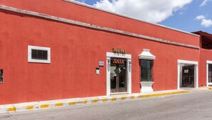 A red building with a sign reading "Hotel Rath" and a window with a metal gate.