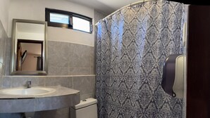 A bathroom with a sink, mirror, and shower curtain.