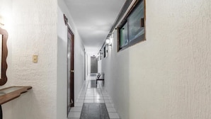 A hallway with white walls, a tiled floor, and a wooden bench on the left.