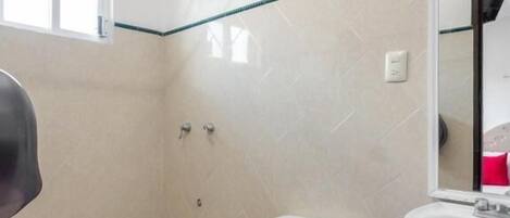 Un baño con inodoro, lavamanos y zona de ducha.