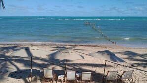 A beach with several sun umbrellas and beach chairs. - Flor de Lis Exclusive Hotel (Maceió)