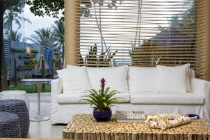 A white sofa with cushions, a potted plant, and a wooden coffee table with a book and a decorative item.