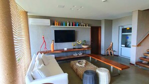 A modern living room with a sofa, coffee table, and a TV mounted on the wall. - Flor de Lis Exclusive Hotel (Maceió)