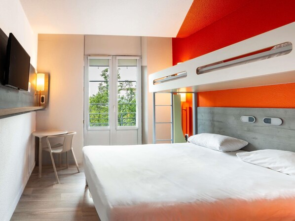 Una habitación de hotel moderna con una cama litera, un escritorio y un televisor.