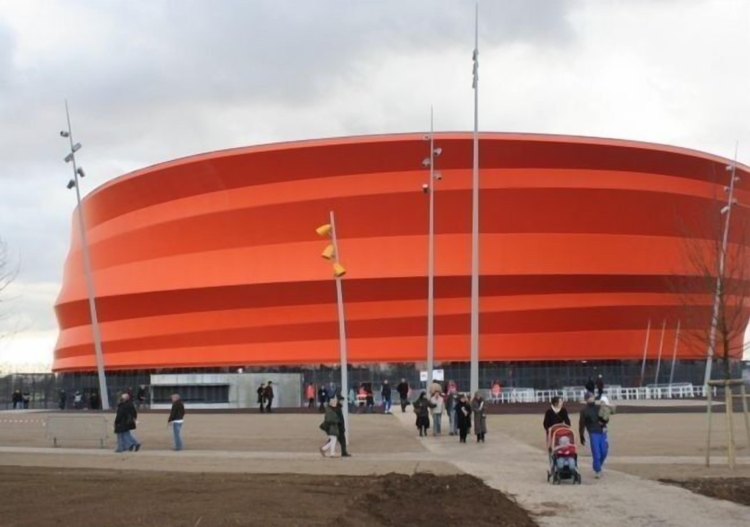 A large, circular, red stadium with multiple tiers of seating.