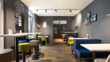 L’intérieur d’un café moderne, avec un plancher en bois, des sièges aux couleurs vives et une lumière naturelle abondante grâce à de grandes fenêtres.