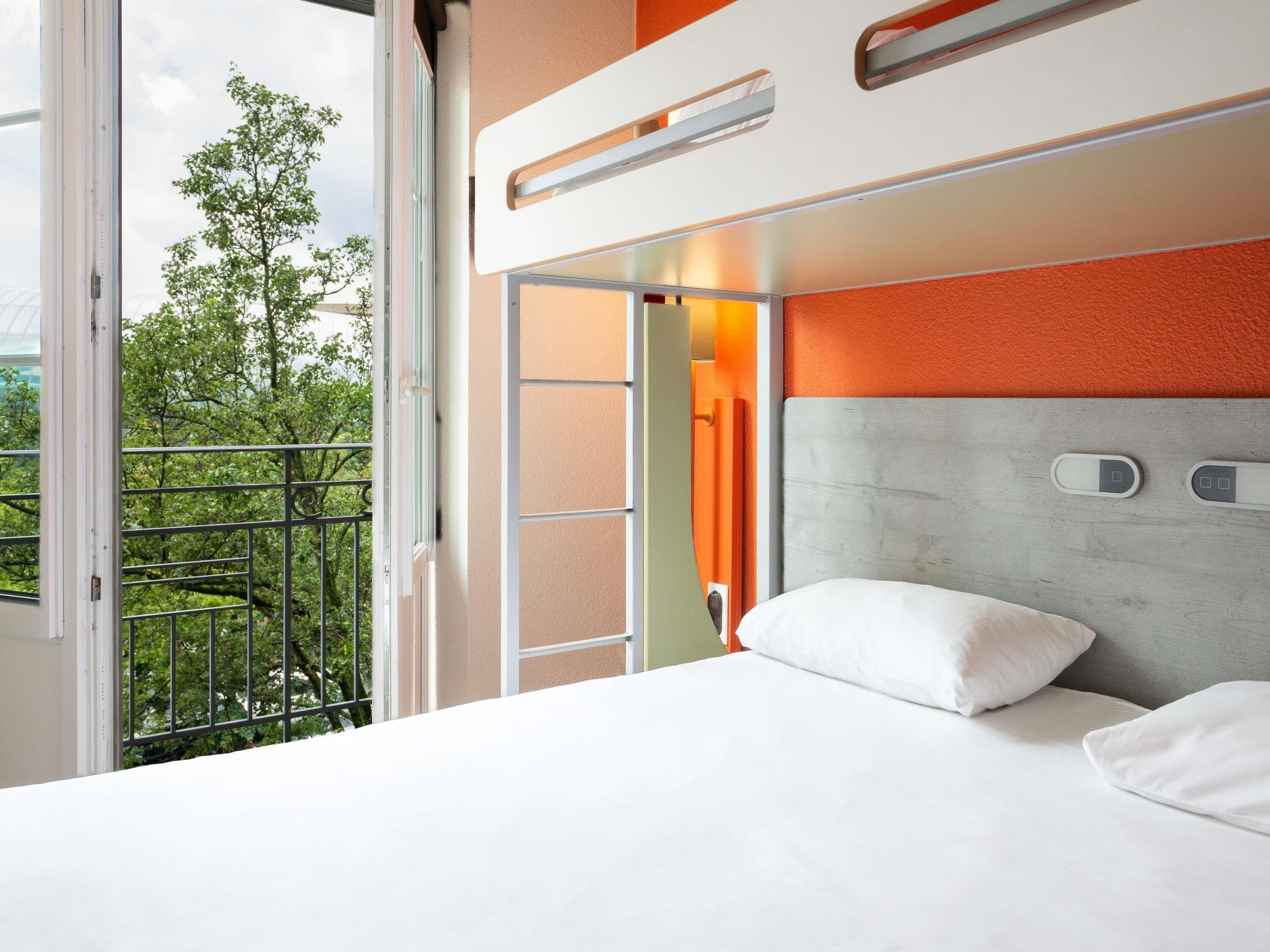 A hotel room with a balcony, a bed with white bedding, and a modern headboard.