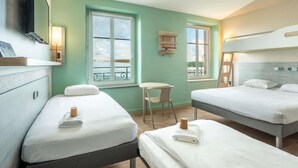A hotel room with two beds, a small table, a chair, a TV, and a window with a view of a balcony.