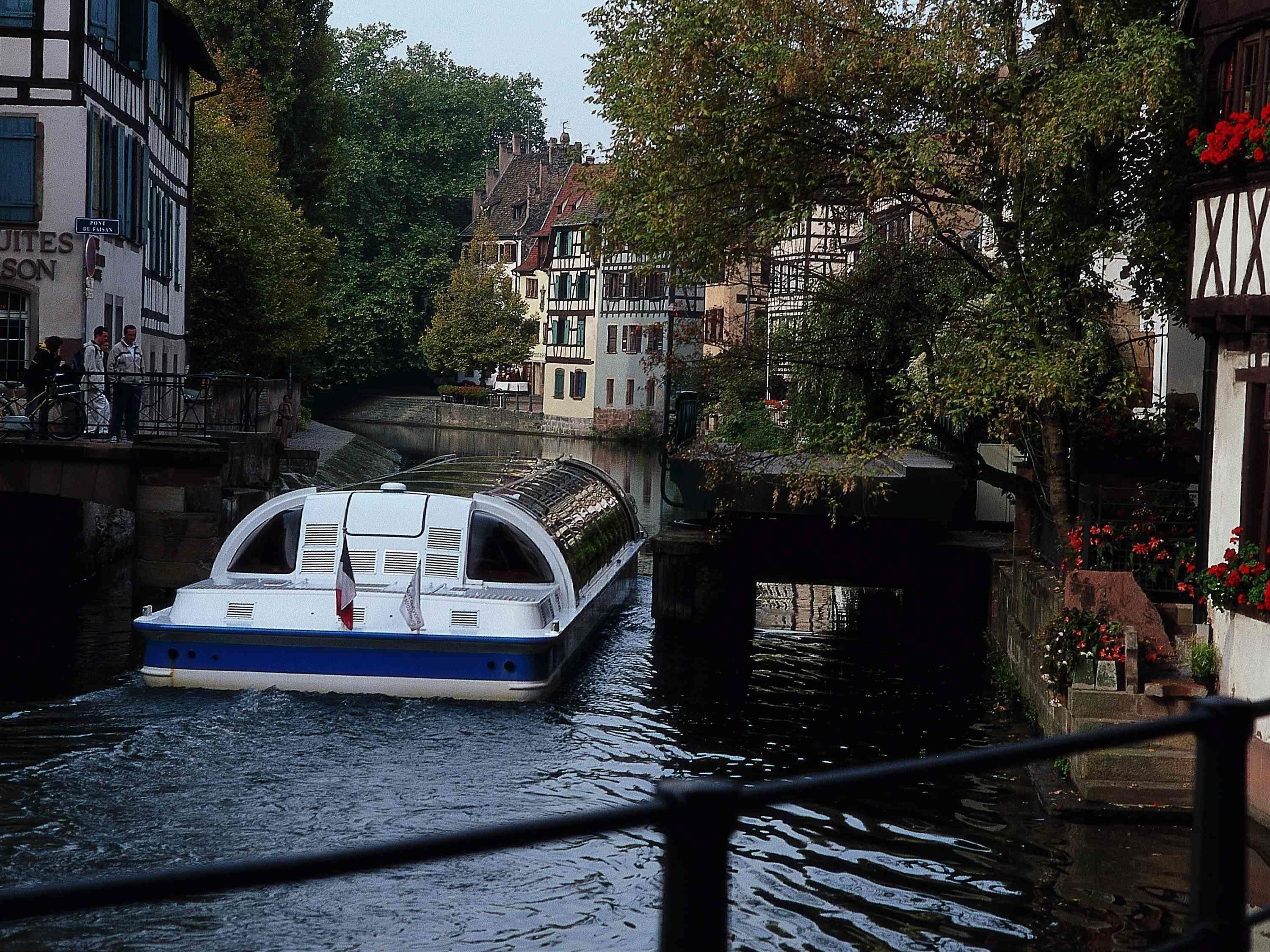 Un canal étroit, avec un bateau, des bâtiments de chaque côté et un pont.
