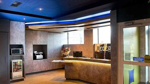 A reception area with a counter, a microwave, a vending machine, and a window with a view.