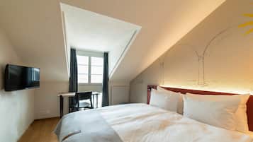 A hotel room with a bed, a desk, a chair, a TV, and a window.