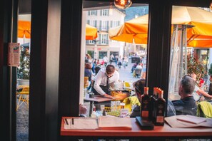 An outdoor café with tables and chairs, umbrellas, and people dining. - Boutique Hotel Stockalperhof (Brig)
