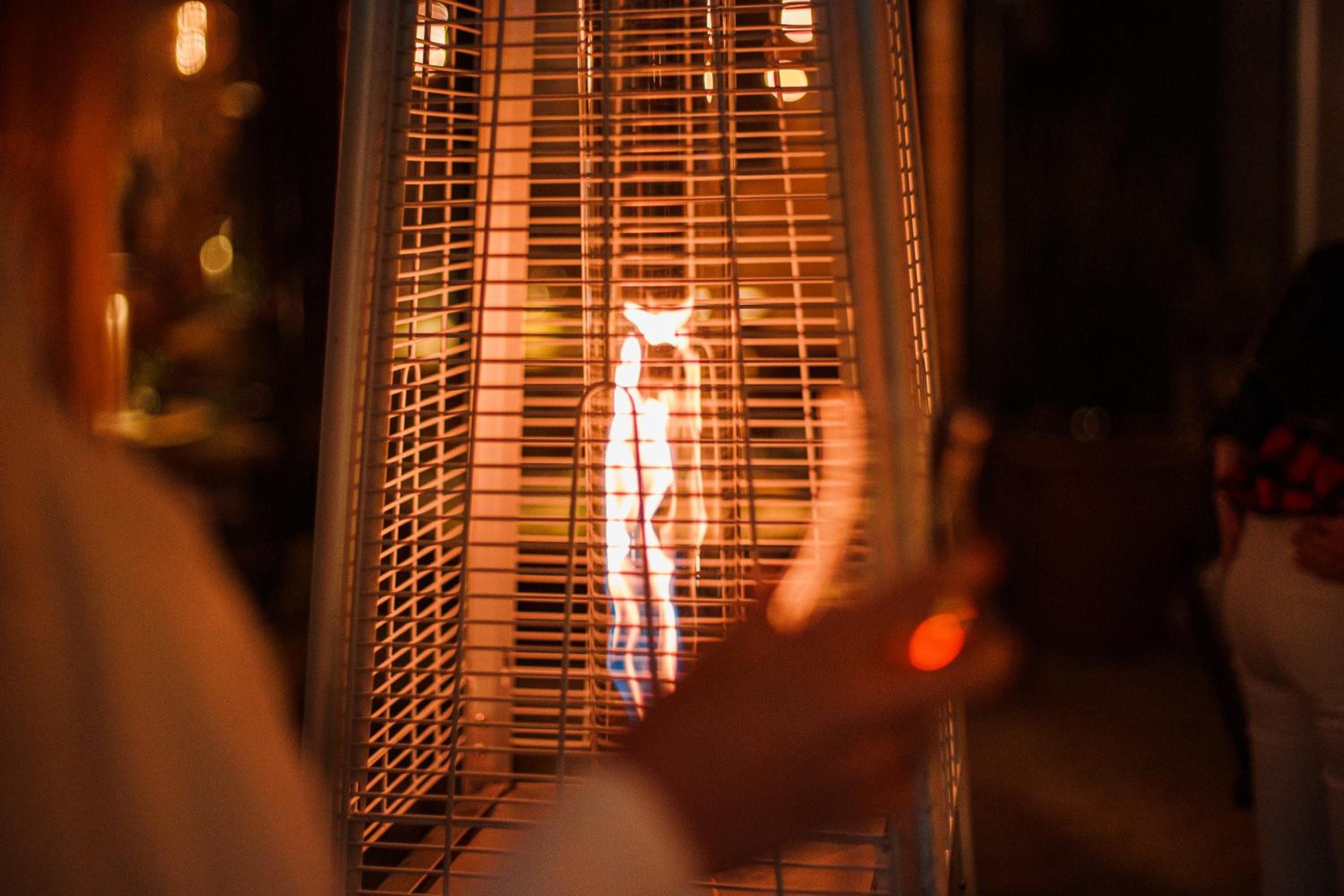 Une personne tenant un verre dans lequel on peut apercevoir une lumière chaude, peut-être provenant d’une boisson.