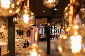 A restaurant interior with wooden crates as decor, hanging lights, and a bar area in the background. - Boutique Hotel Stockalperhof (Brig)
