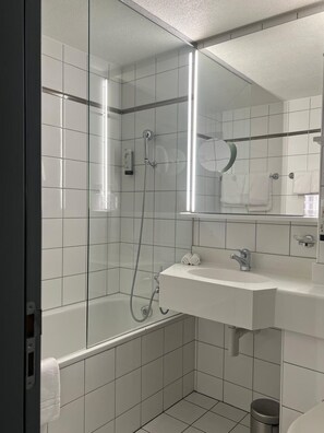 Une salle de bain moderne avec une douche à parois de verre, un lavabo blanc et un miroir au-dessus du lavabo.
