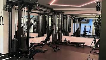 Une salle de sport équipée de matériel de musculation, de miroirs et dotée d’un sol recouvert d’une moquette rouge.