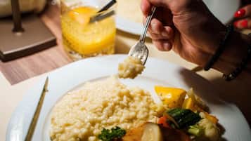 A person serving rice with vegetables on a plate.