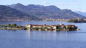 Un pueblo a orillas del lago con edificios históricos, una iglesia destacada y montañas al fondo.